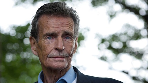 Ein älterer Mann mit grauen Haaren und Schnäuzer