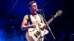Frontmann der Band auf der Bühne mit Gitarre