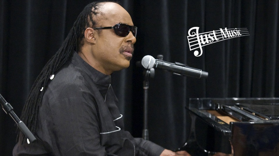 Stevie Wonder am Klavier mit Mikro und Just Music-Logo