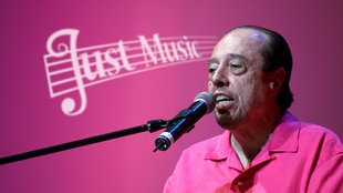 Sergio Mendes vor pinkem Hintergund mit Just Music-Logo