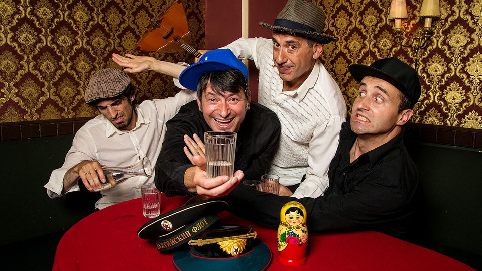 Band Apparatschik an einem Tisch mit Wodka, Matrjoschka und Balalaika