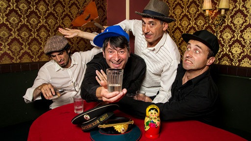 Band Apparatschik an einem Tisch mit Wodka, Matrjoschka und Balalaika