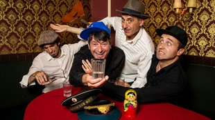 Band Apparatschik an einem Tisch mit Wodka, Matrjoschka und Balalaika