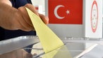 Eine Person wirft einen Stimmzettel in Deutschland für eine Wahl in der Türkei in eine Wahlbox