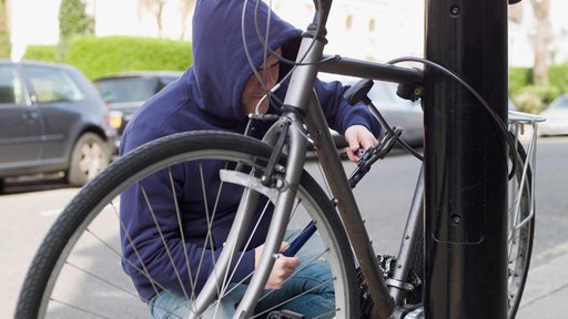 Mann bricht Fahrradschloss mit einem Seitenschneider auf