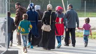 Eine Gruppe von Flüchtlingen ghet durch ein Tor