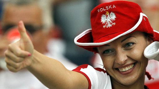 Eine Frau mit Fan-Hut auf dem "Polska" steht