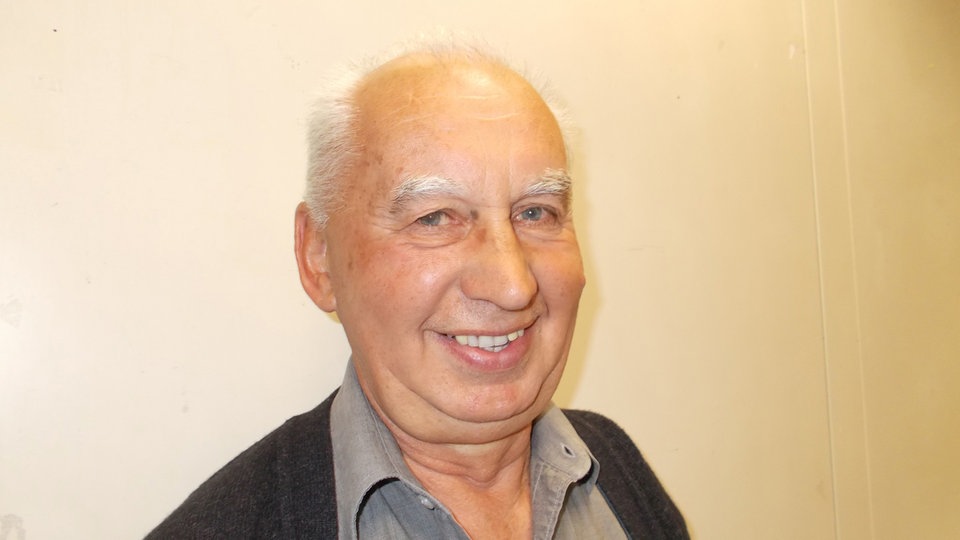 Branko Višak, portret sa širokim osmijehom - ispred zida svijetle boje 