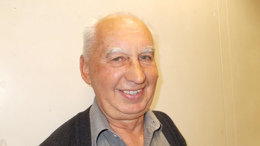 Branko Višak, portret sa širokim osmijehom - ispred zida svijetle boje 