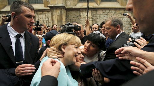  Angela Merkel, novinari, građani koji je fotografiraju - i tjelohranitelji