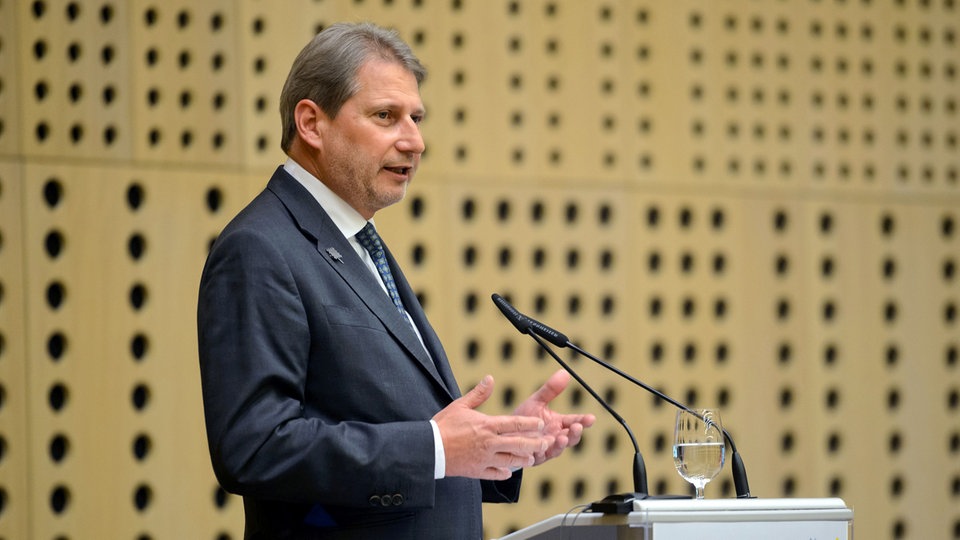 Johannes Hahn stoji za govornicom, pred mikrofonom