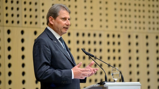 Johannes Hahn stoji za govornicom, pred mikrofonom