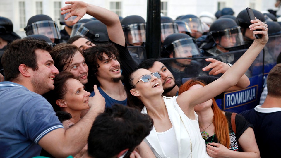 Grupa devojaka i mladića pravi "selfie" prd kordonom policije