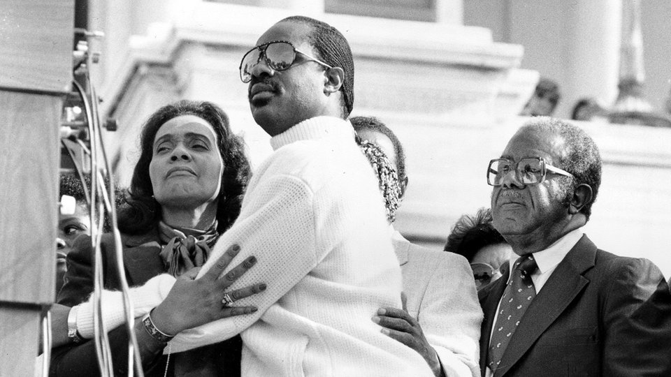 Bildrechte: pa/AP Stevie Wonder und Coretta King 1983 als Präsident Ronald Reagen das Gesetz zum Martin Luther King Tag unterschreibt