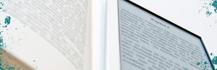 Ein aufgeklapptes Buch mit einem E-Book auf der rechten Seite liegend